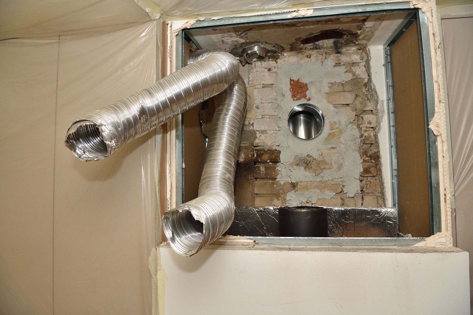 Vue intérieure de l'ouverture de la cheminée avec conduit métallique flexible.