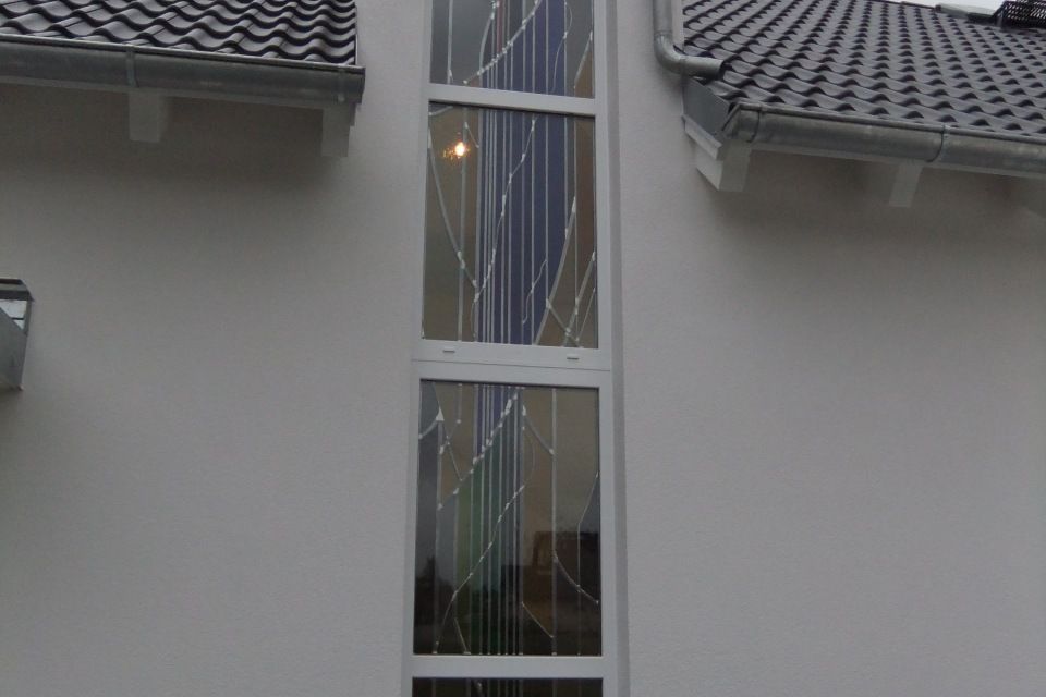 Längliche Glasfläche mit Bleiverglasung an einem Wohnhaus