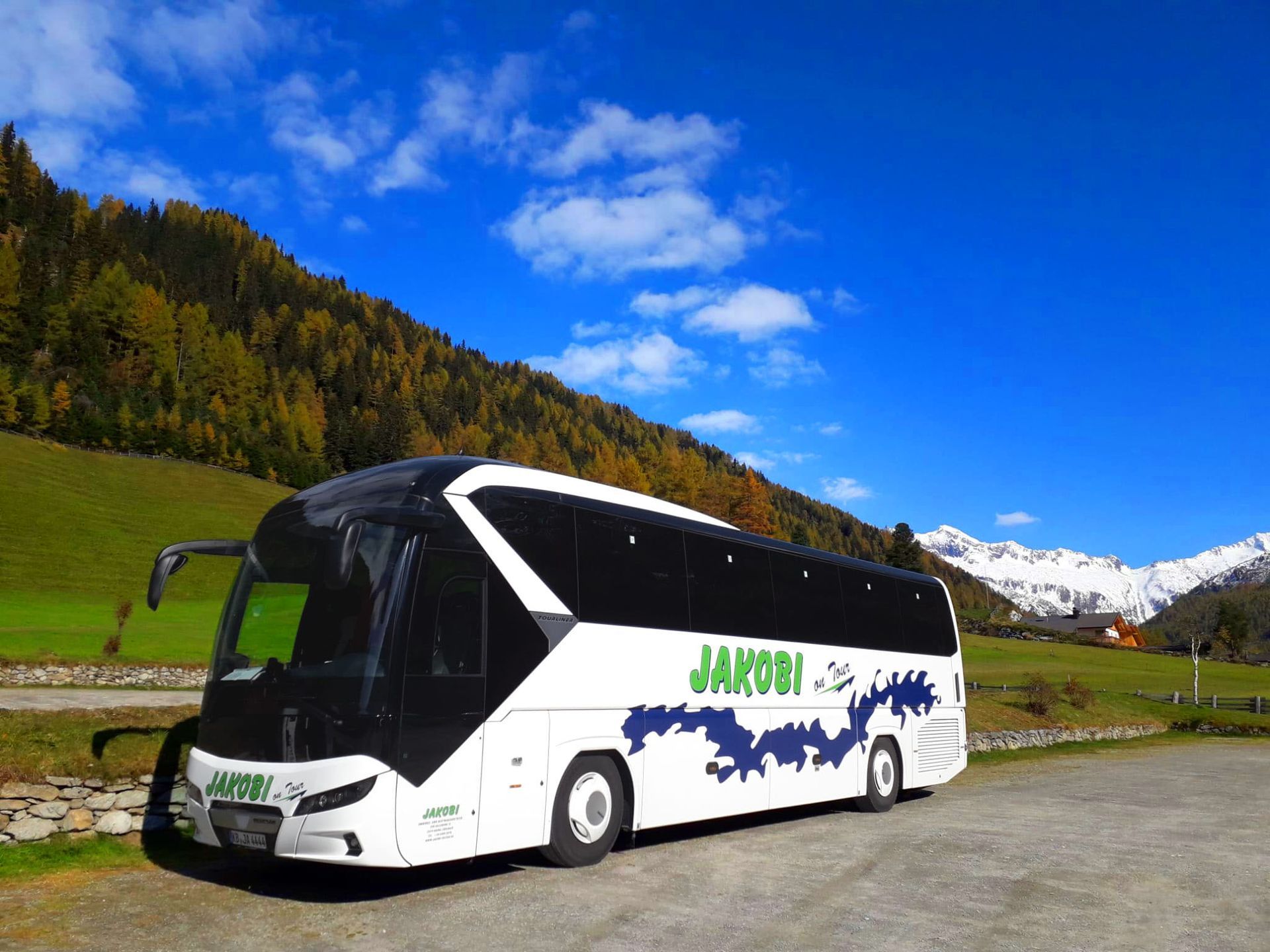 Ein weiß-schwarzer Bus parkt vor einem Berg.