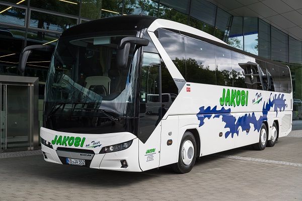 Vor einem Gebäude parkt ein weiß - schwarzer Bus mit der Aufschrift „ Jakobi “ auf der Seite.