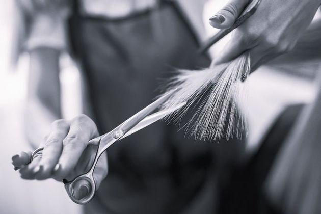 Una mujer se corta el pelo con tijeras en una foto en blanco y negro.