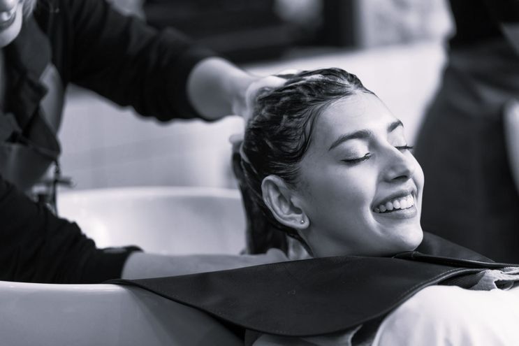 Una mujer se está lavando el cabello en una peluquería.
