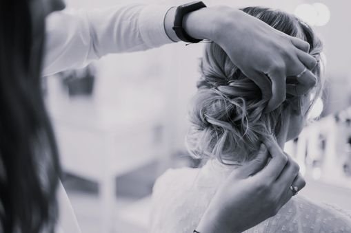 En una foto en blanco y negro, una mujer se está peinando en la peluquería.