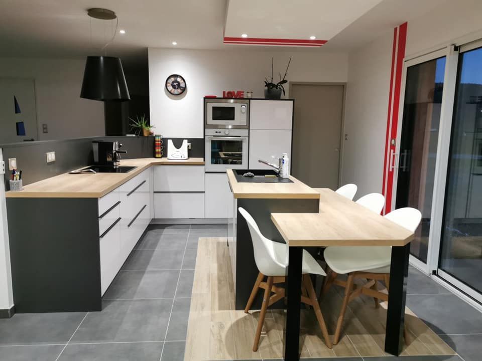 Une cuisine moderne avec des armoires blanches, des comptoirs couleur bois, des touches de gris foncé et une table à manger avec des chaises blanches.