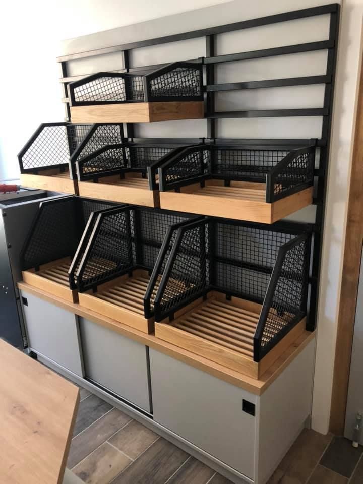 Un présentoir de vente au détail avec des étagères en bois et en métal noir, comprenant un meuble bas en bois, utilisé pour présenter des marchandises.