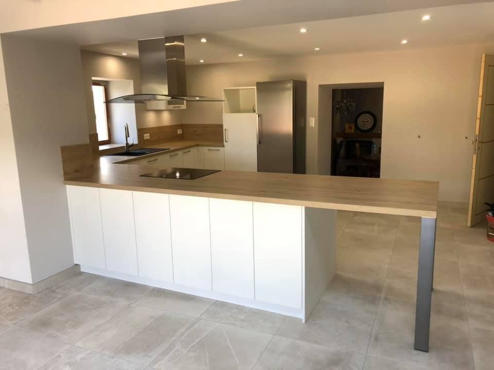 Cuisine moderne avec armoires blanches, comptoir en bois clair, appareils électroménagers en acier inoxydable et sol carrelé.