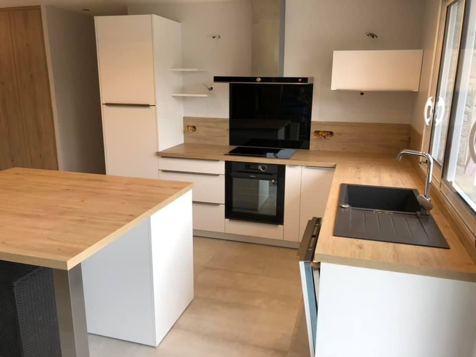 Une cuisine moderne avec des armoires blanches, des comptoirs couleur bois, une cuisinière noire et un évier noir assorti.