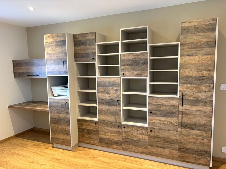 Une commode en bois à deux rangées de tiroirs, surmontée d'une plante en pot et de petits objets décoratifs, dans une chambre.