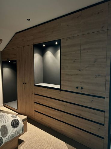 Deux meubles de rangement en bois et blanc, munis de tiroirs, sont posés sur un sol carrelé à motifs, avec une étagère et des éléments décoratifs au mur au-dessus.