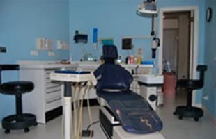 Un consultorio dental con paredes azules y un sillón dental.