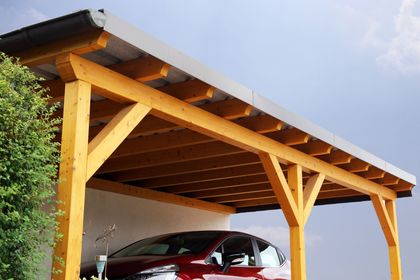 Carport en bois avec voiture rouge garée dessous