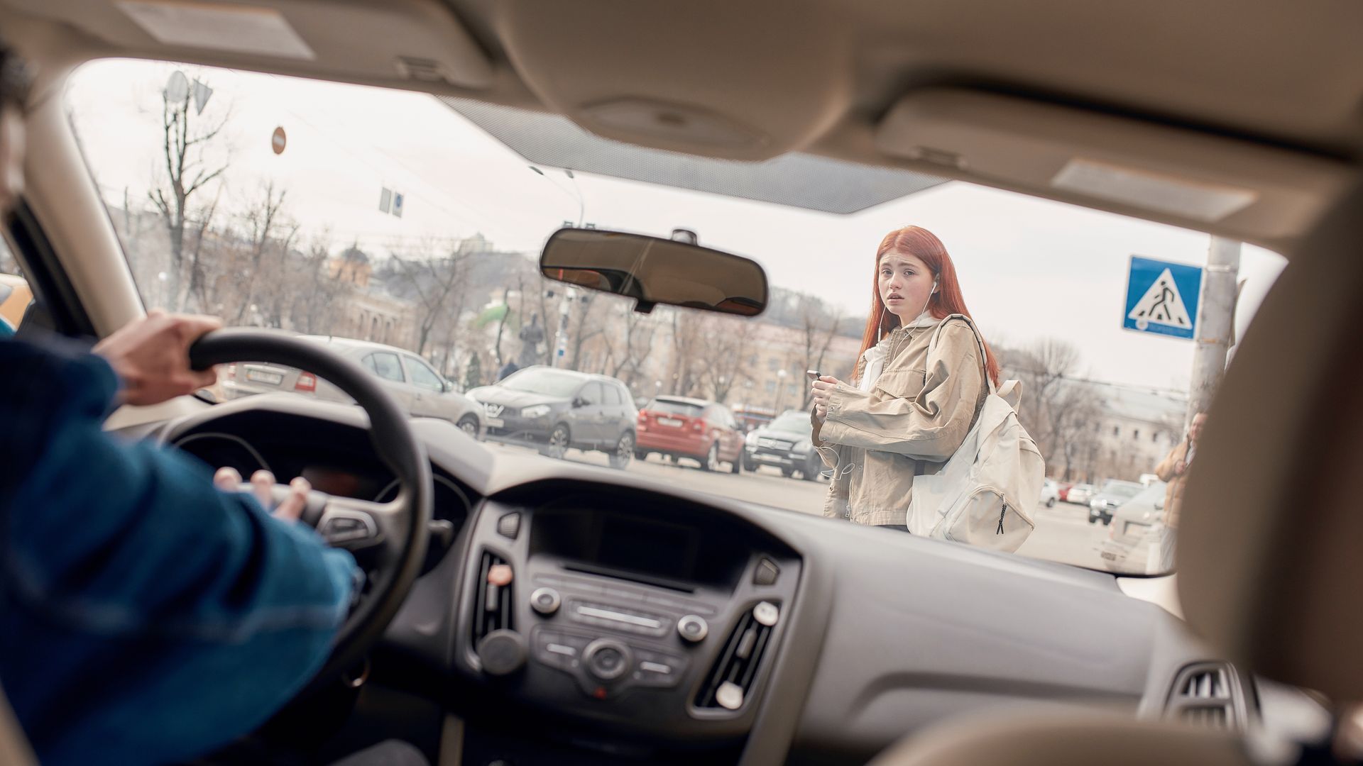 Femme en train de traverser la route  avec son téléphone à la main obligeant la voiture à freiner