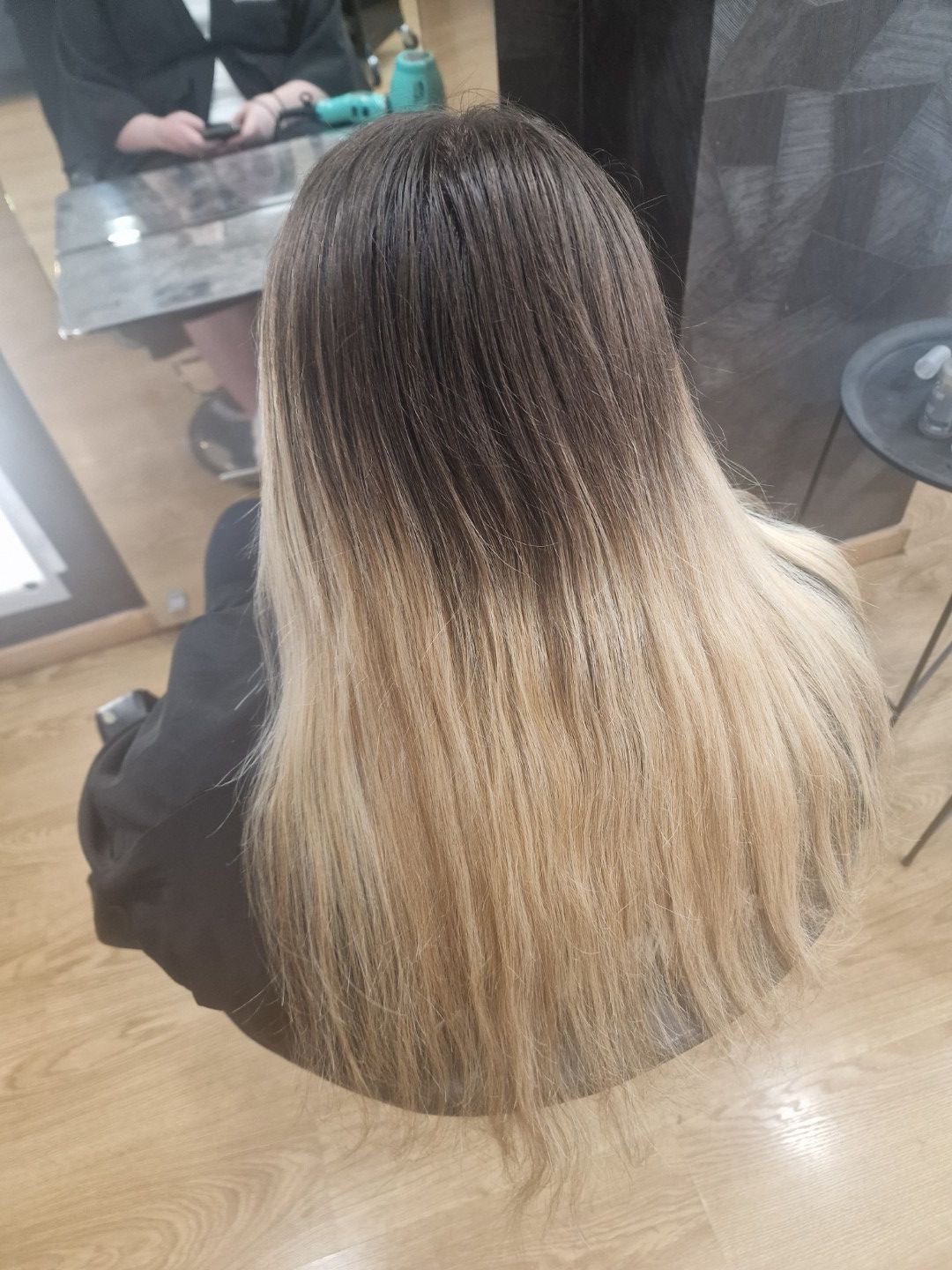 Cabello largo con efecto ombré, desde castaño oscuro hasta rubio, visto desde arriba en una silla de peluquería.