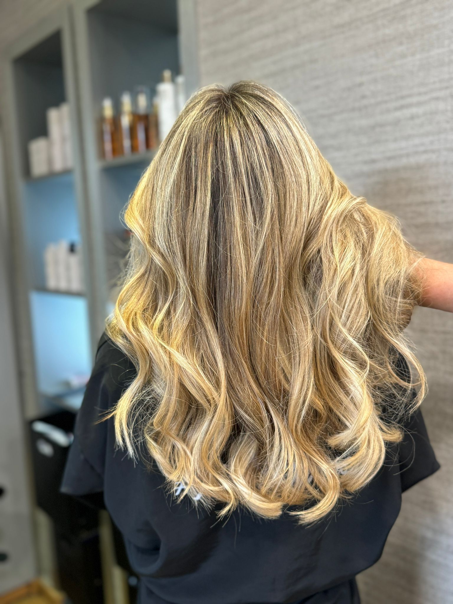 Cabello rubio largo y ondulado peinado en rizos sueltos en una silla de peluquería.