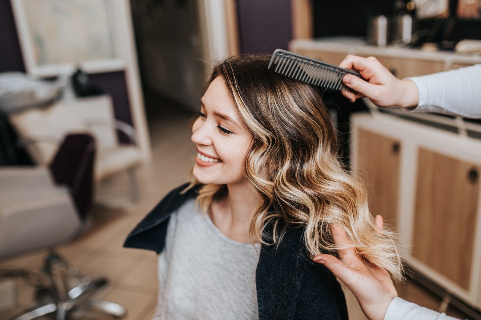 Mujer sonriendo mientras le cepillan el pelo en una peluquería.