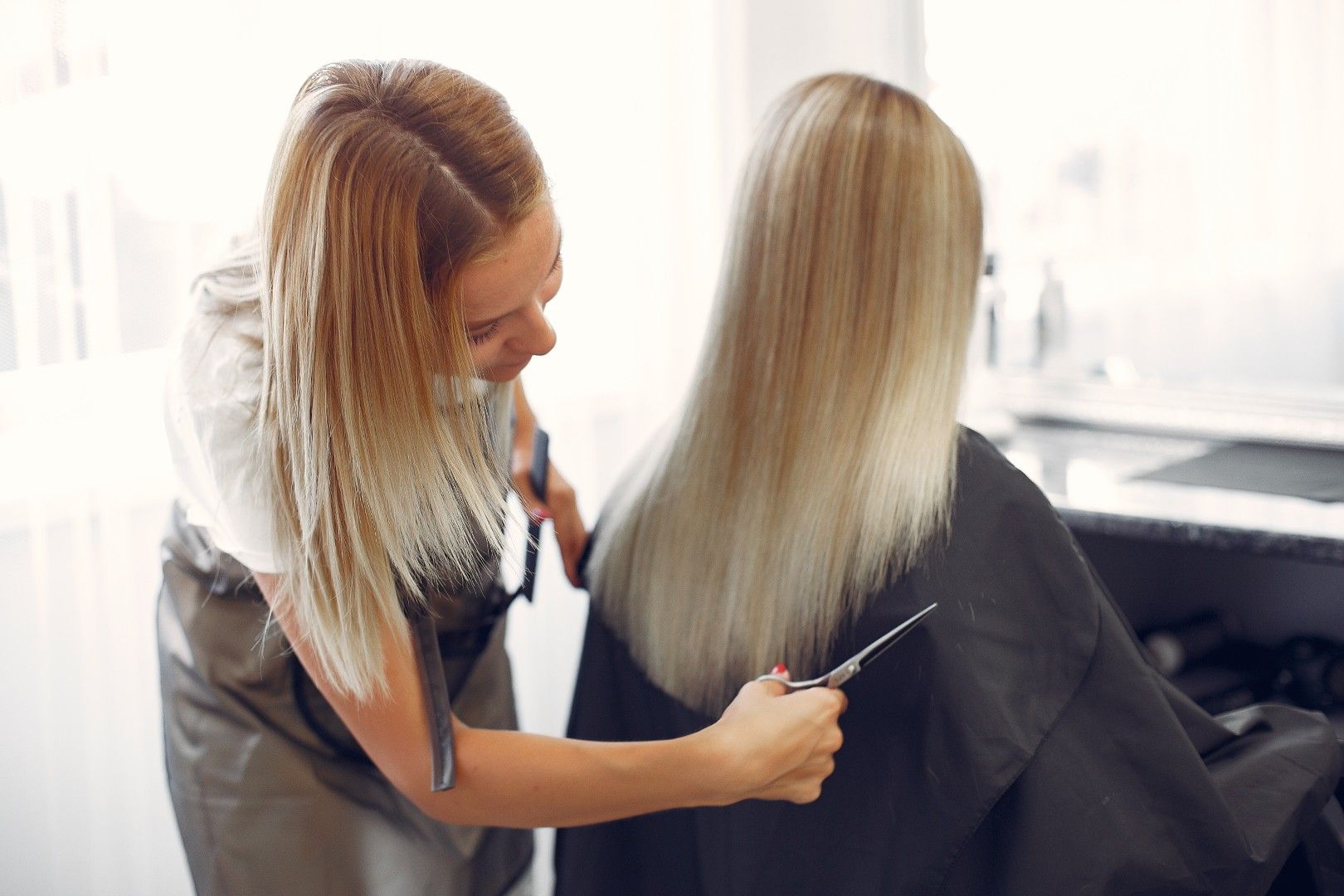 Peluquera peinando el largo cabello rubio de una clienta en un salón de belleza.