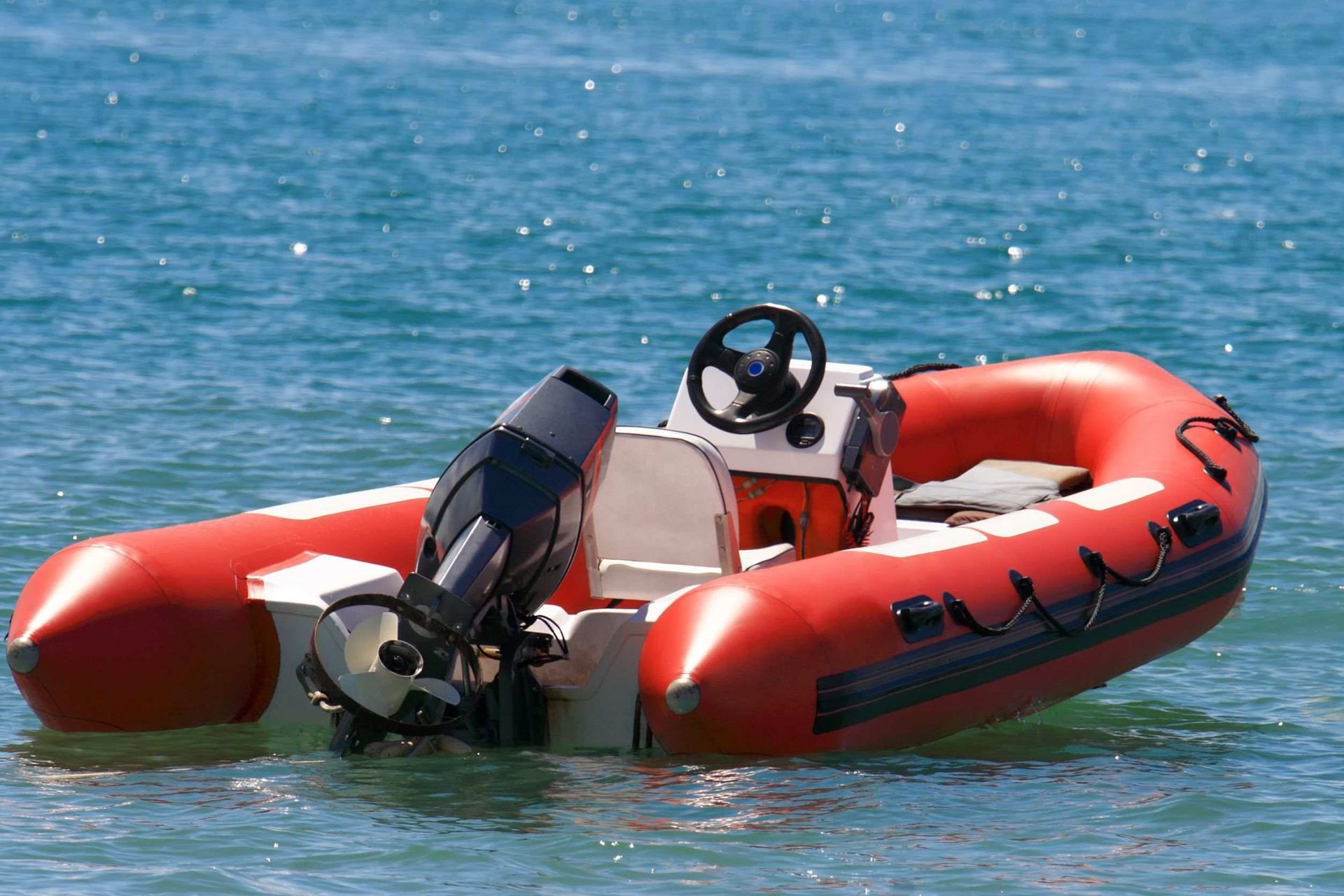 Un barco rojo con un volante está en el agua.