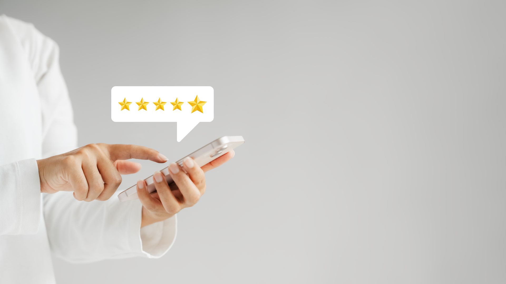 Personne tenant un smartphone, touchant l'écran, avec une bulle de dialogue montrant cinq étoiles dorées.