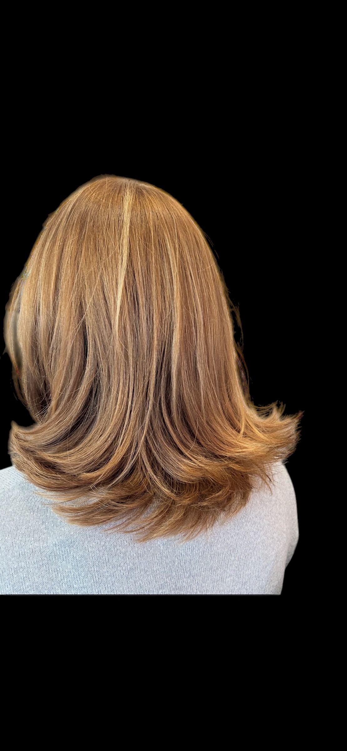 Eine Frau mit langen braunen Haaren sitzt auf einem Stuhl vor einem Spiegel. Foto von der Hairstyling Ricci e Capricci GmbH
