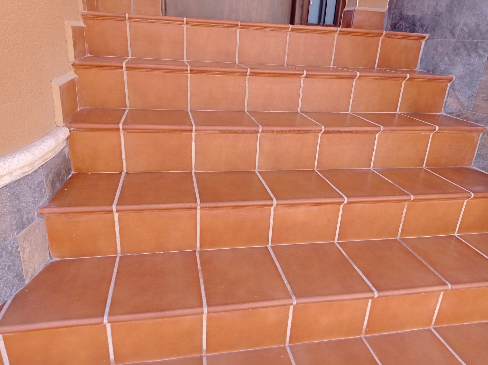 Una escalera exterior revestida de baldosas de color terracota que conduce a un rellano.