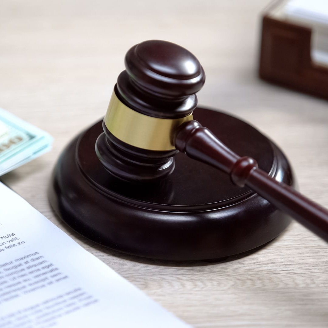 Un maillet en bois posé sur un bloc solide, à côté d'un document et de l'argent.