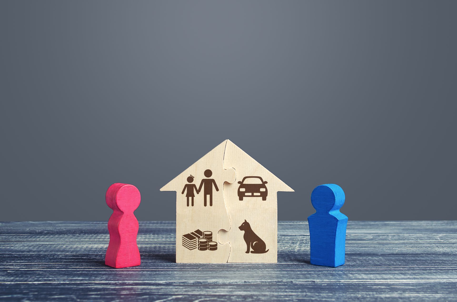 Des silhouettes roses et bleues font face à une maison avec une famille, une voiture, un chien et des cartons à l'intérieur ; concept de divorce.