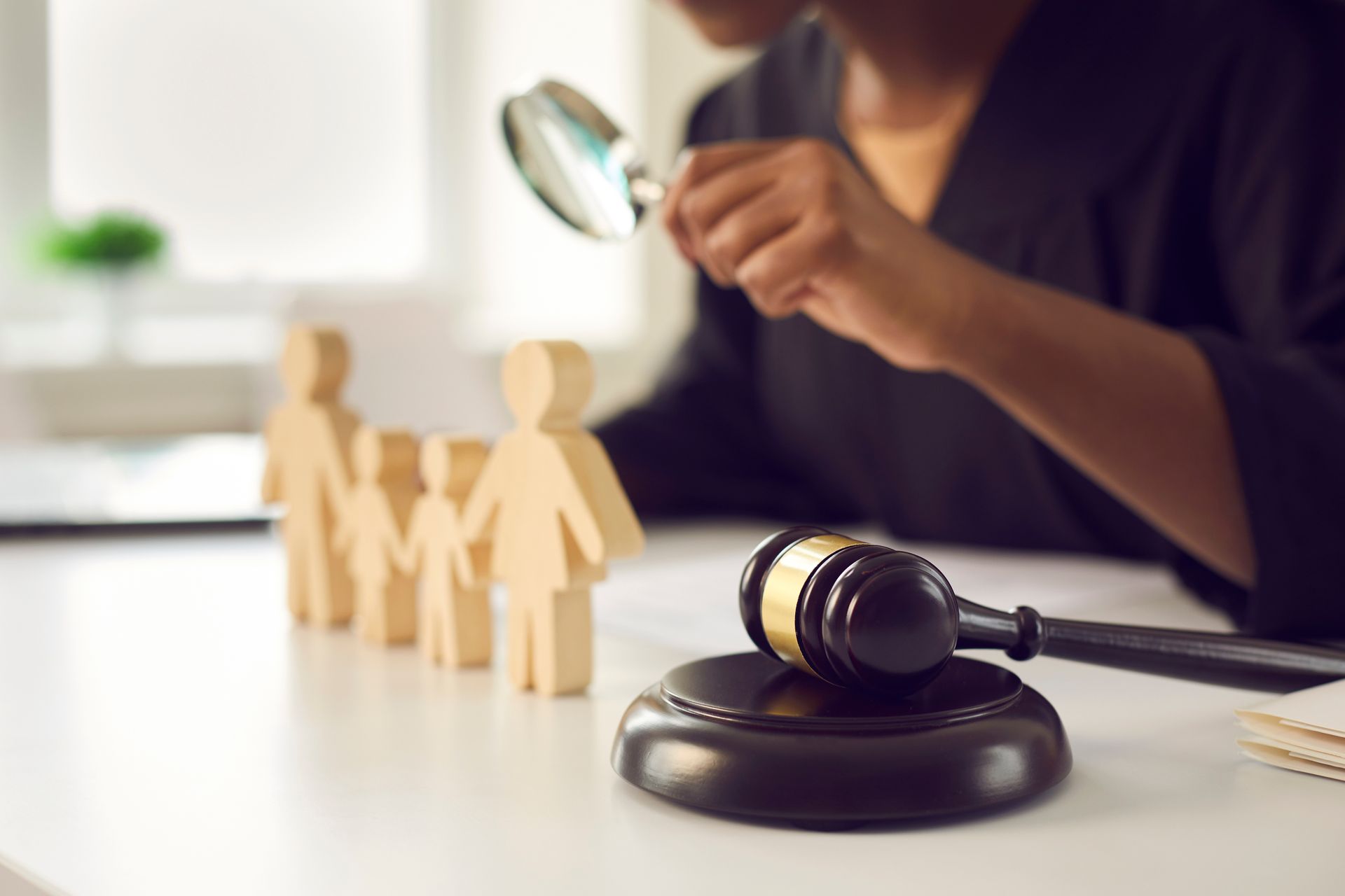 Figurines familiales en bois, maillet, loupe, sur une table.