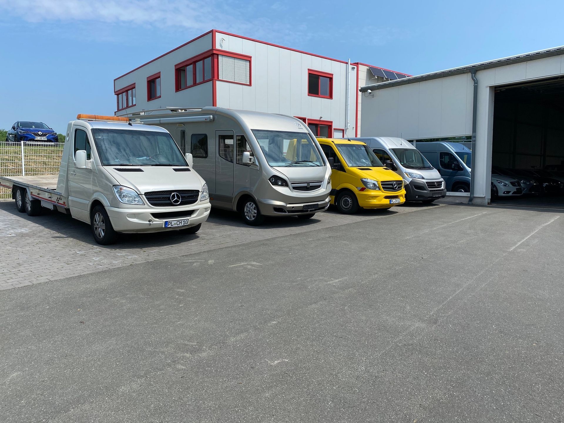 An einem sonnigen Tag parkten mehrere Lieferwagen vor einem Gebäude.