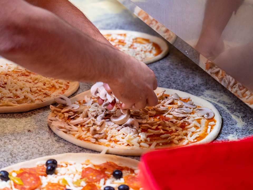 putting toppings on pizza