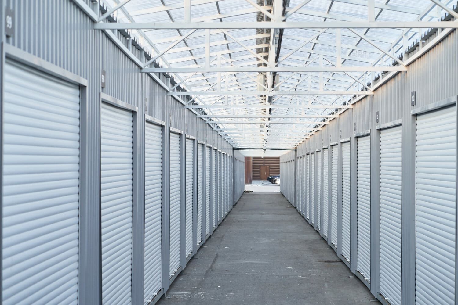 Un largo pasillo lleno de filas de unidades de almacenamiento con puertas blancas.