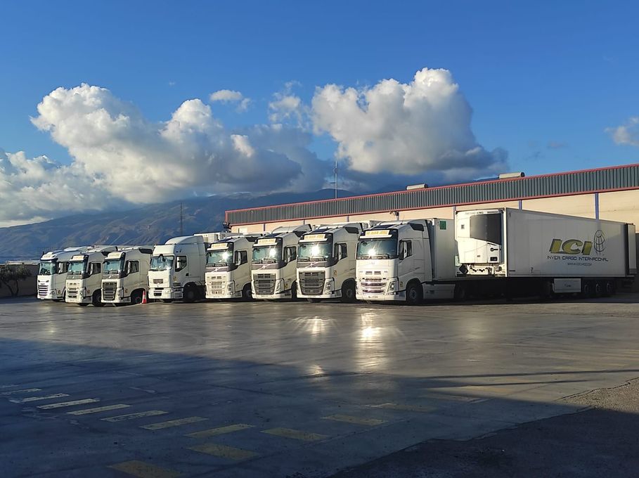 Una fila de camiones están estacionados frente a un edificio.
