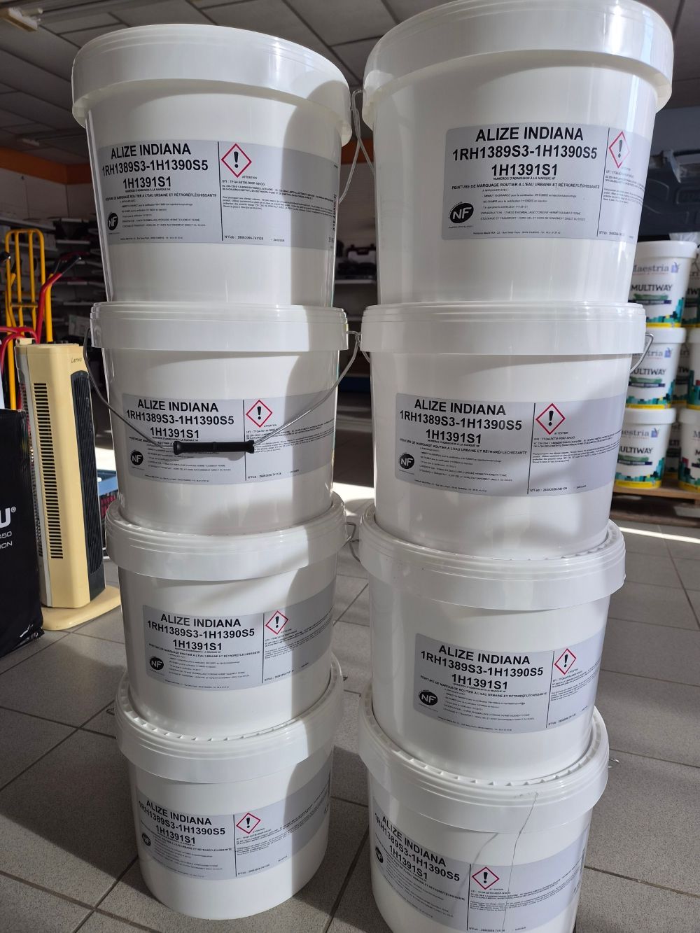 Seaux en plastique blanc empilés avec des étiquettes imprimées dans une zone de stockage industrielle