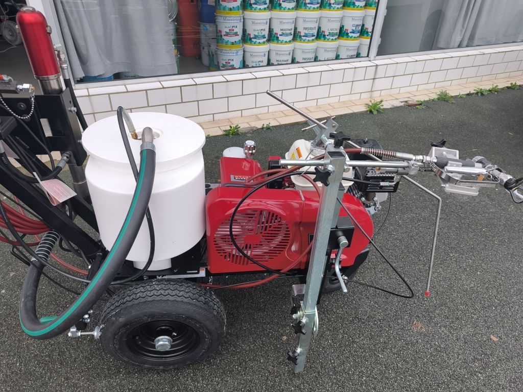 Pulvérisateur à peinture avec tuyau et réservoir blanc sur le trottoir à côté d'une vitrine de magasin
