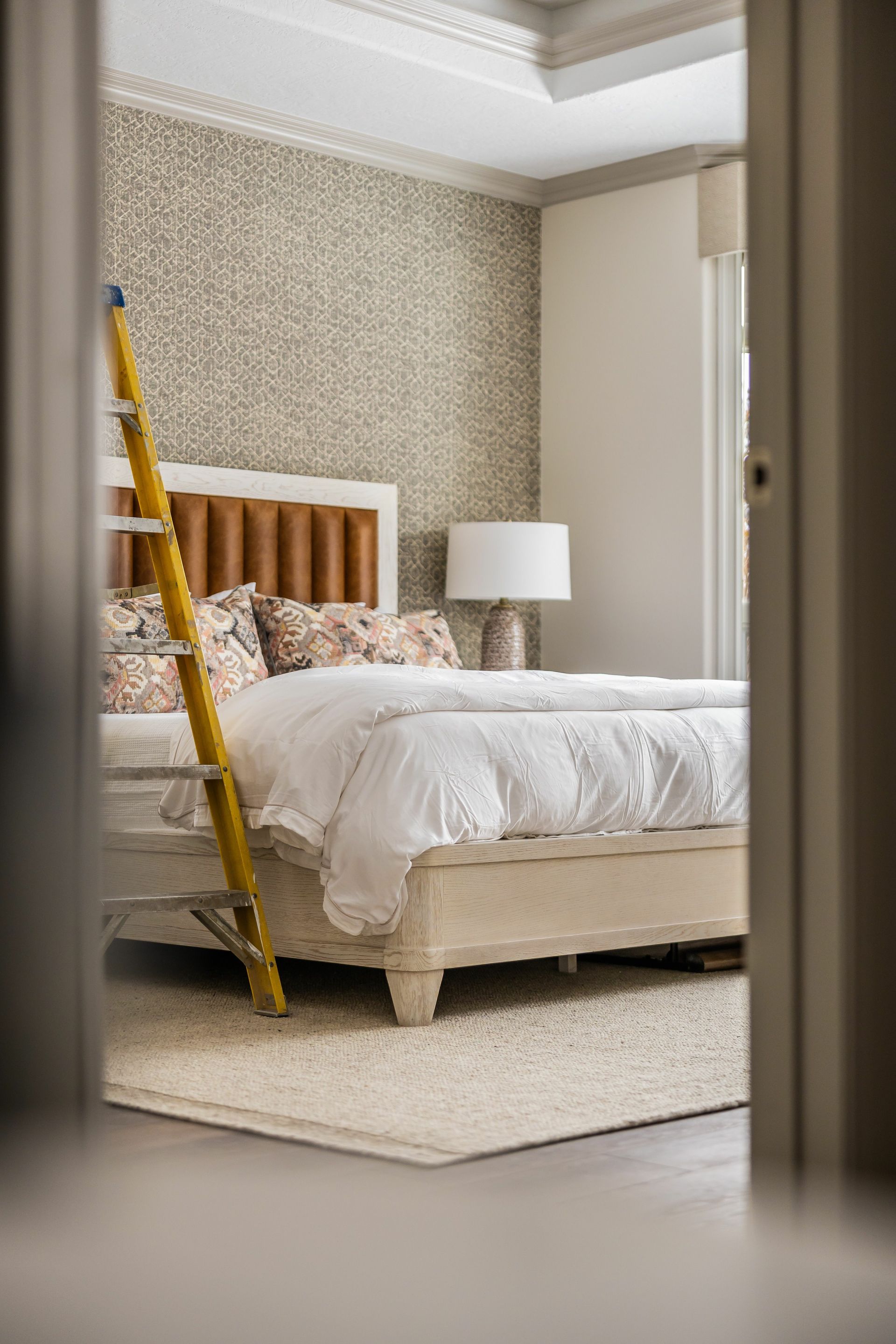 Une chambre avec un lit, une lampe et une échelle.