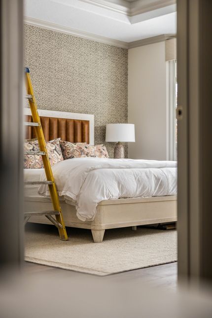 Une chambre avec un lit, une lampe et une échelle.