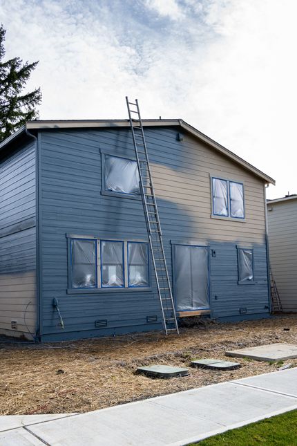 Une maison est en train d'être peinte avec une échelle attachée dessus.