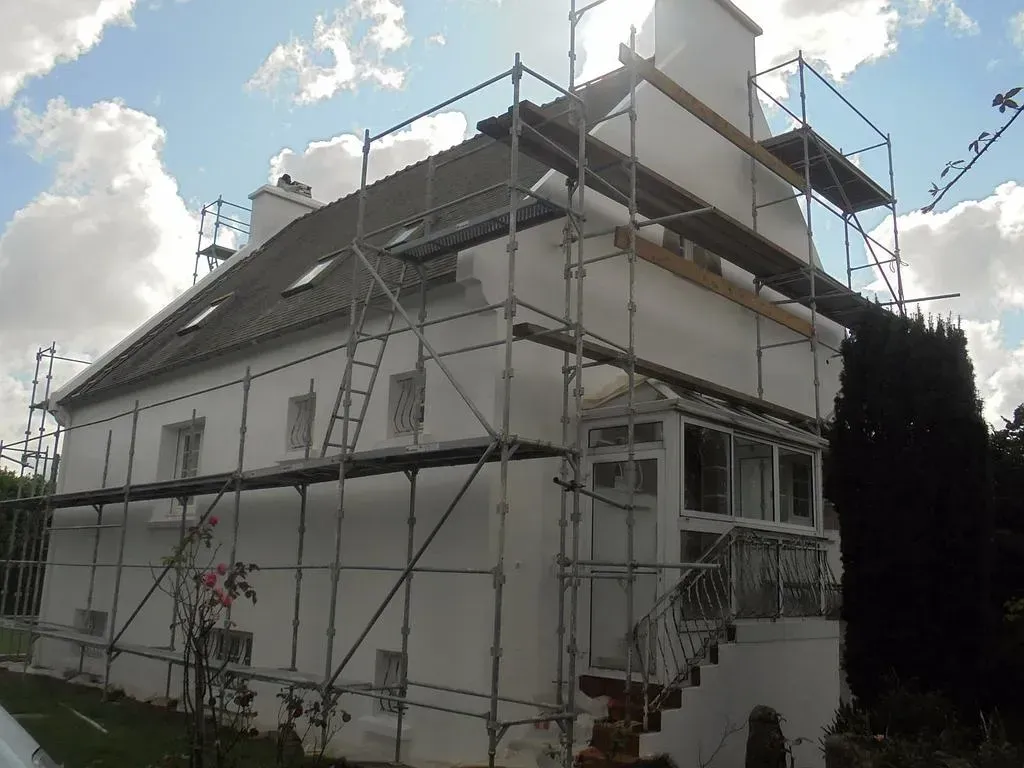 Petite maison avec un échafaudage autour pendant un ravalement