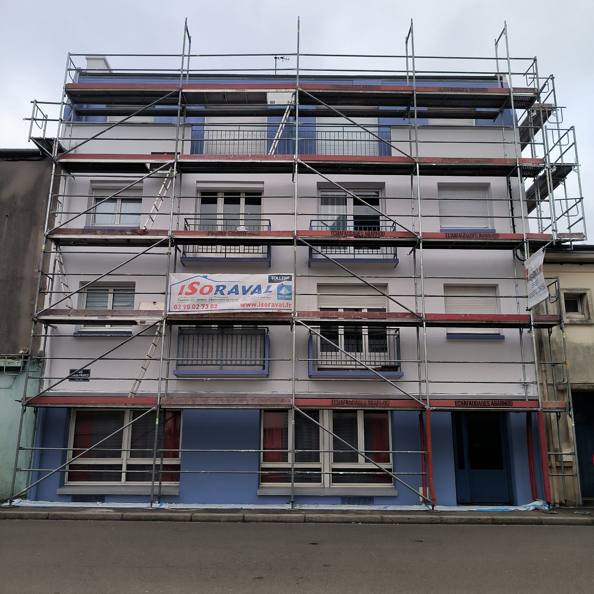 Une main gantée applique un produit hydrophobe à l'aide d'un pinceau brosse sur un mur en brique