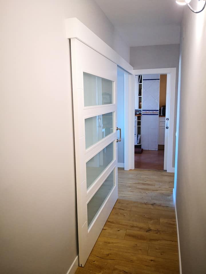 Un pasillo con una puerta corrediza de vidrio que conduce a una cocina.