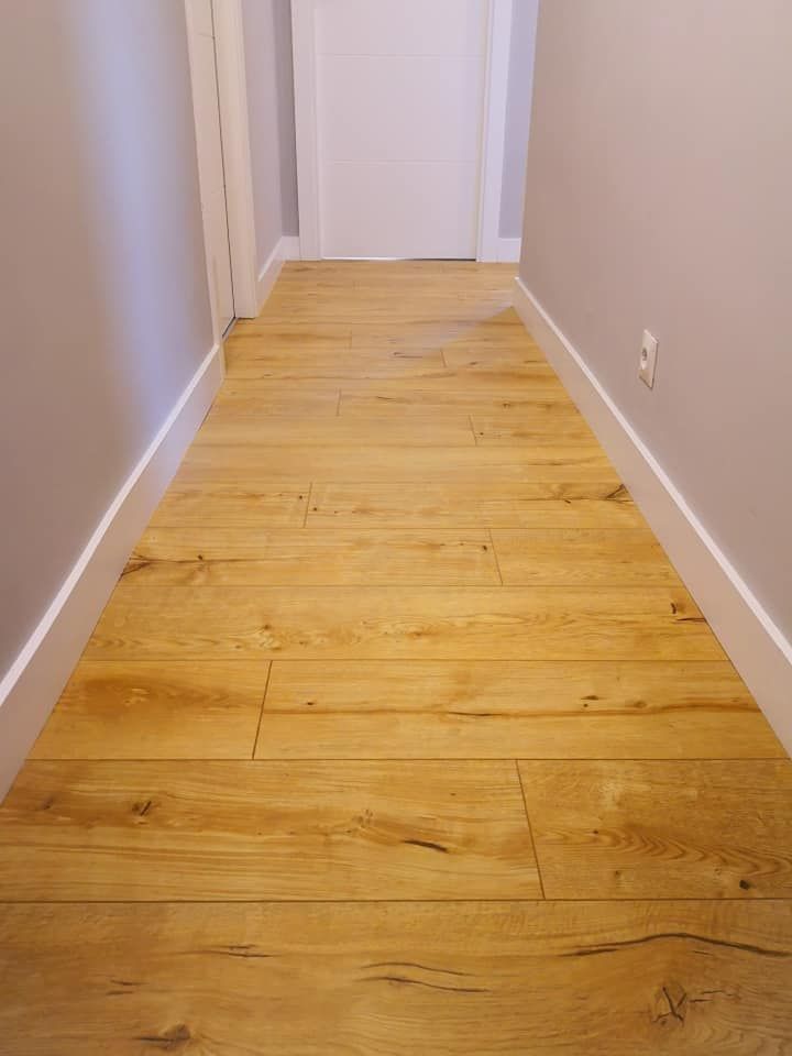 Un pasillo con suelo de madera y paredes blancas.