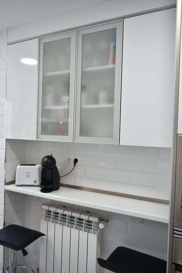 Una cocina con gabinetes blancos y un horno tostador.