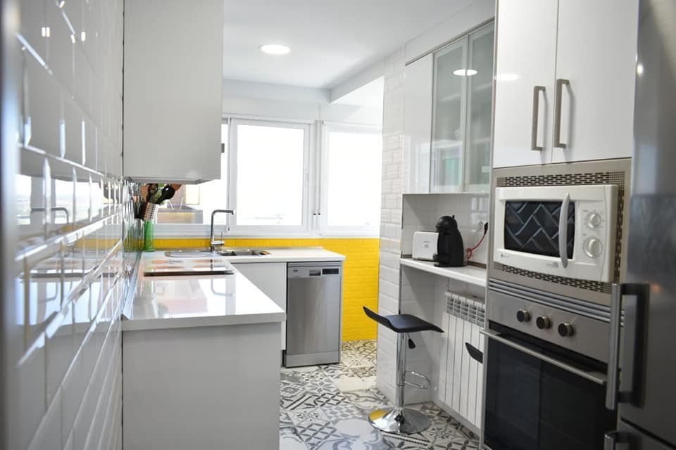 Una cocina con gabinetes blancos y electrodomésticos de acero inoxidable.