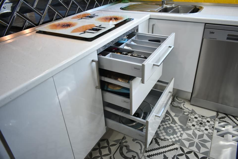 Una cocina con gabinetes blancos y cajones abiertos.