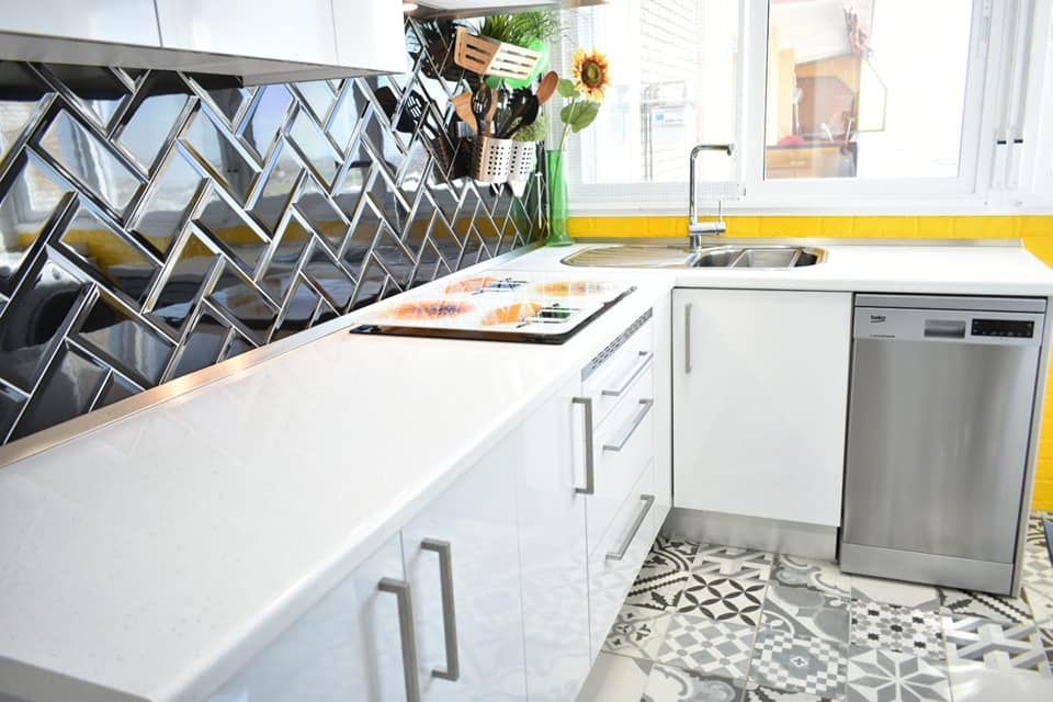 Una cocina con gabinetes blancos y lavavajillas de acero inoxidable.