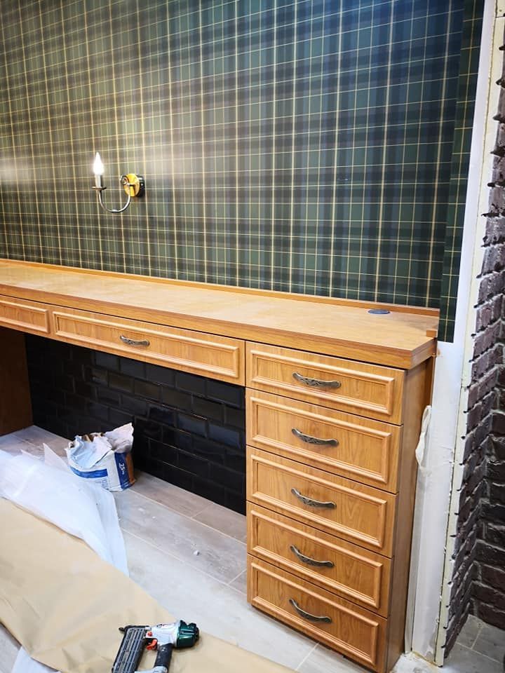 Un escritorio de madera con cajones en una habitación con papel pintado a cuadros.