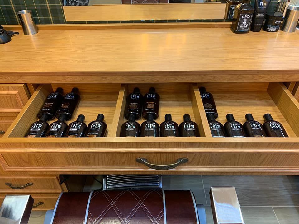 Hay muchas botellas de loción en los cajones de una barbería.