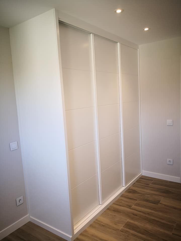 Un dormitorio con armario con puertas correderas y suelo de madera.