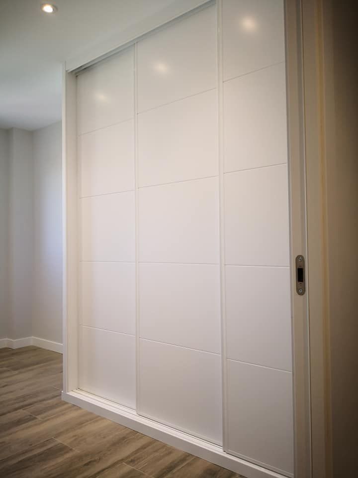 Un armario blanco con puertas correderas en un dormitorio.