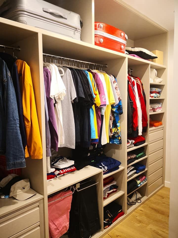 Un vestidor lleno de ropa y una maleta.