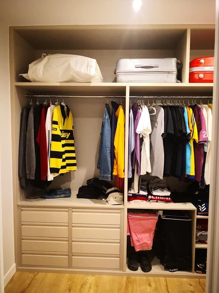 Un armario lleno de ropa y una maleta.